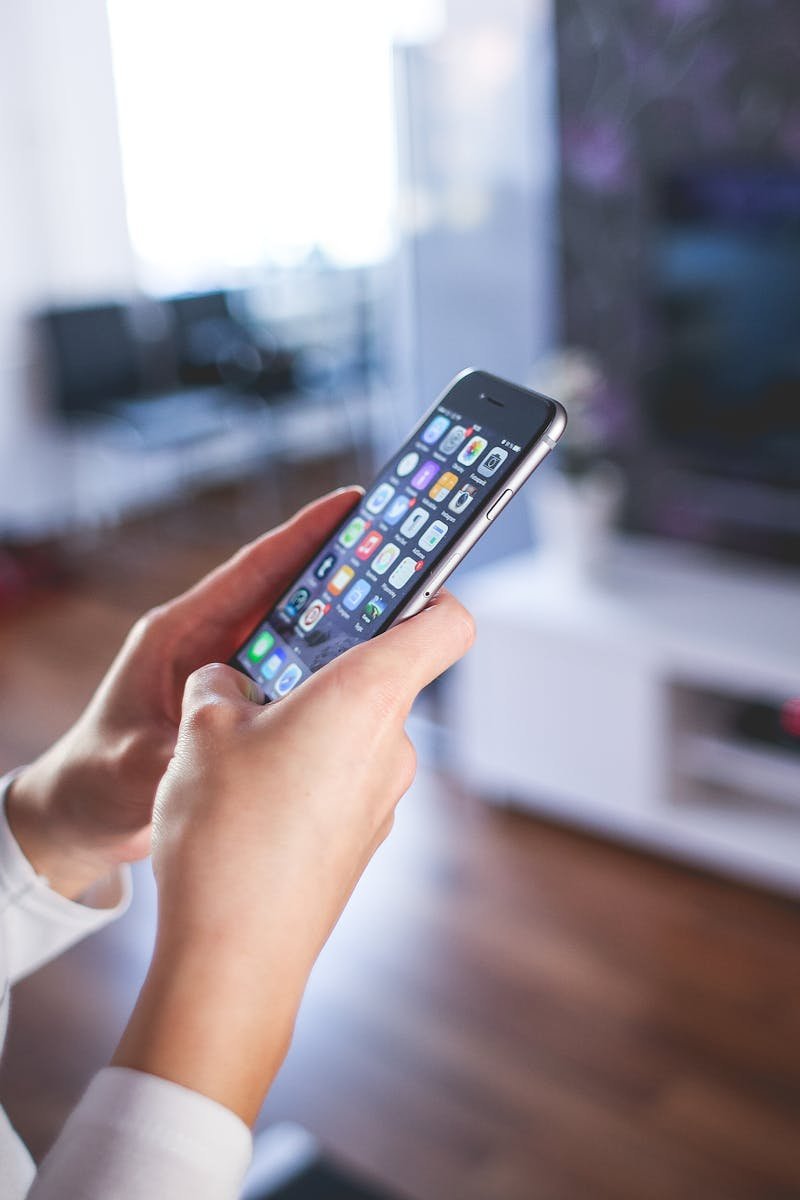 Woman browsing smartphone indoors, highlighting modern technology and communication in a cozy home setting.